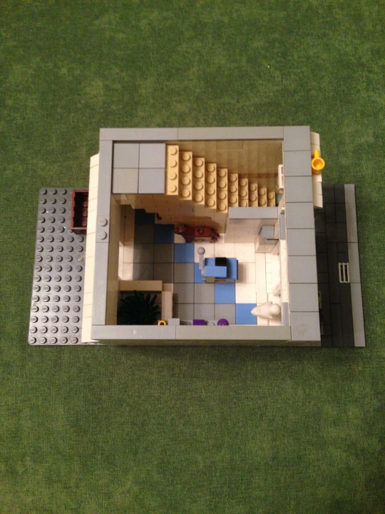 LEGO MOC - New Year's Brick 2014 - Прекрасный Новогодний Домик): Первый этаж-магазин новогодних игрушек.Можно увидеть кассовый аппарат(в центре),собаку(около лестницы) и полочку с товаром.